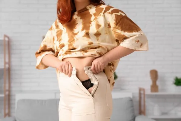 Image of woman trying to do her trousers up after pregnancy weight gain Stockwood